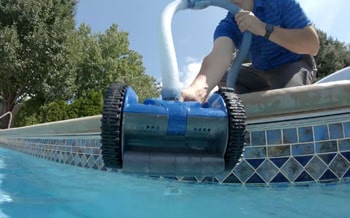 Man with a suction pool cleaner.