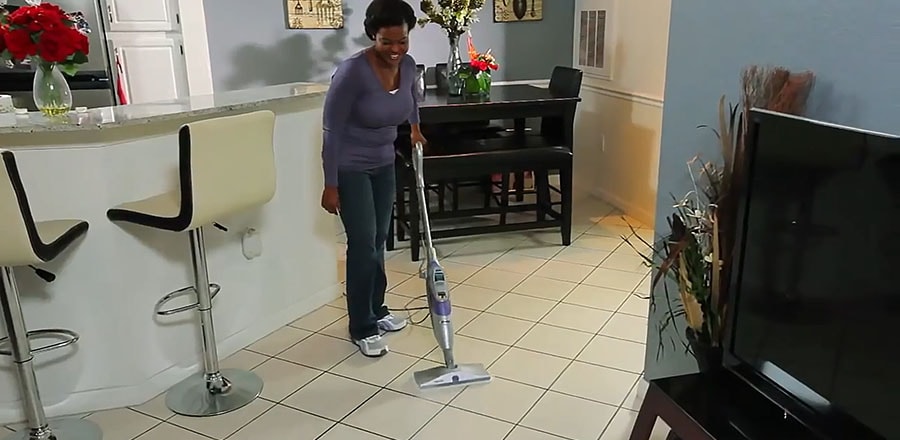 A woman cleans the ceramic floor with a steam mop.