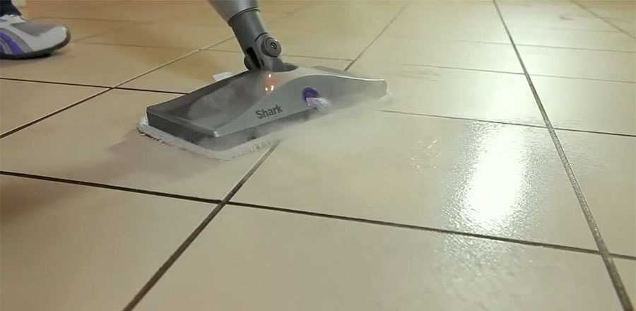 A woman steam mopping a ceramic floor