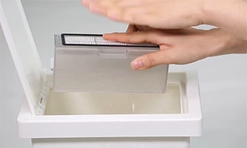 A woman cleans the robot vacuum's dust bin.