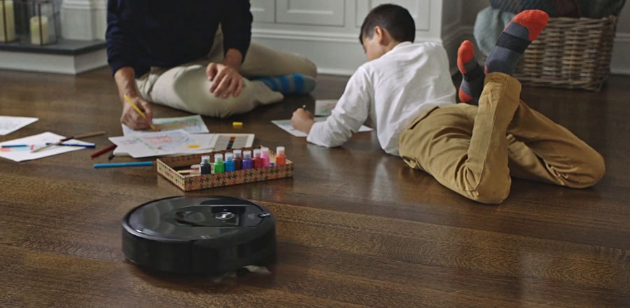 Robot vacuum does its duty near the father and a boy playing together.