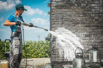 Man cleans a wall using Pressure Washer with a soap.