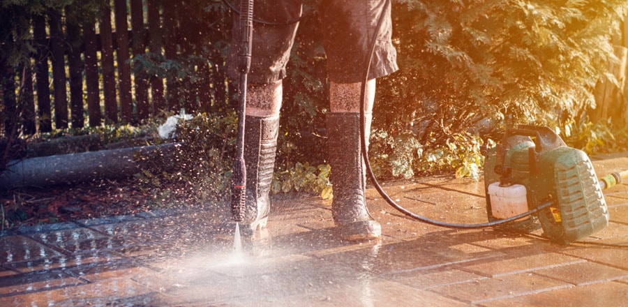 Man wearing protective boots while using pressure washer.