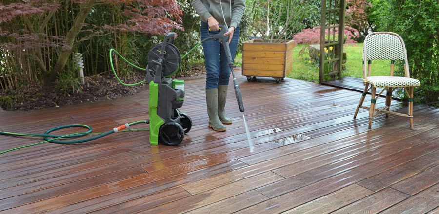 Man cleans his patio with an electric pressure washer.