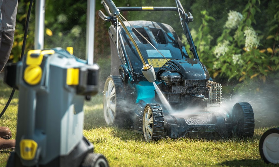 Man washes his lawnmower using electric pressure washer.