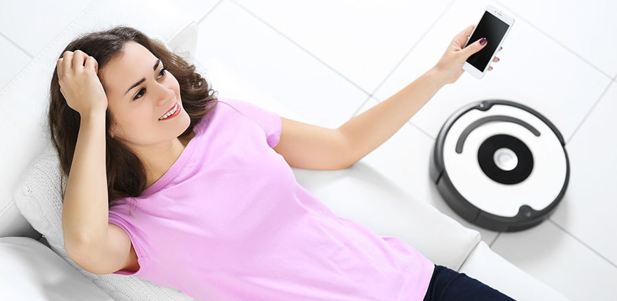 A young woman with a smartphone and a robot vacuum
