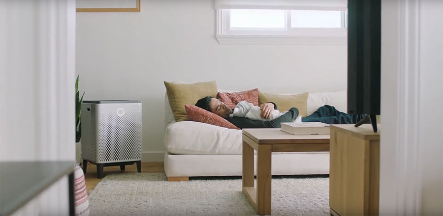 A man sleeping on a couch and a Airmega 400 standing nearby.