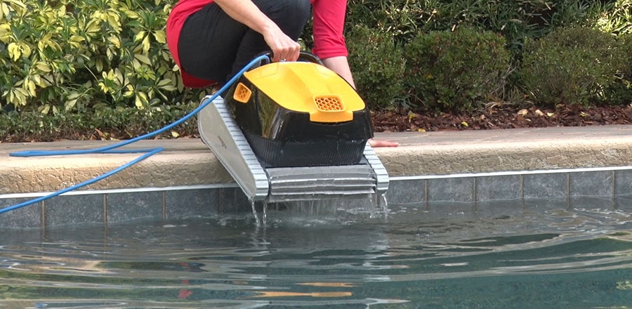 A woman takes the pool robot out of the water