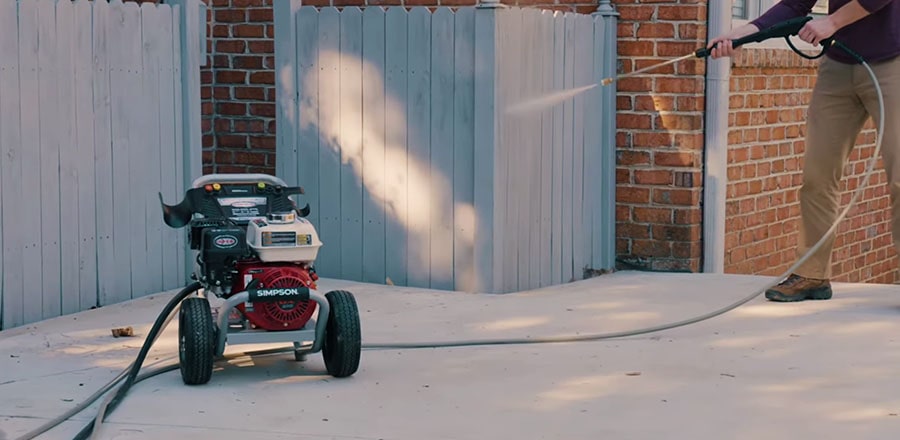 Car Wash Expert Using Water Pressure Washer to Clean a Red Modern