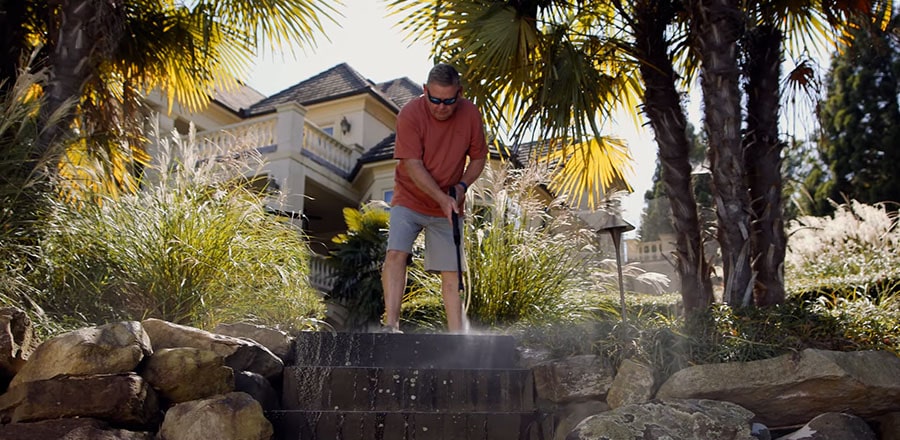 A man cleans the yard with the Greenworks electric pressure washer.