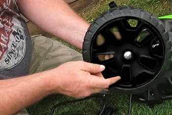 Man attaches wheel to the base of the pressure washer.