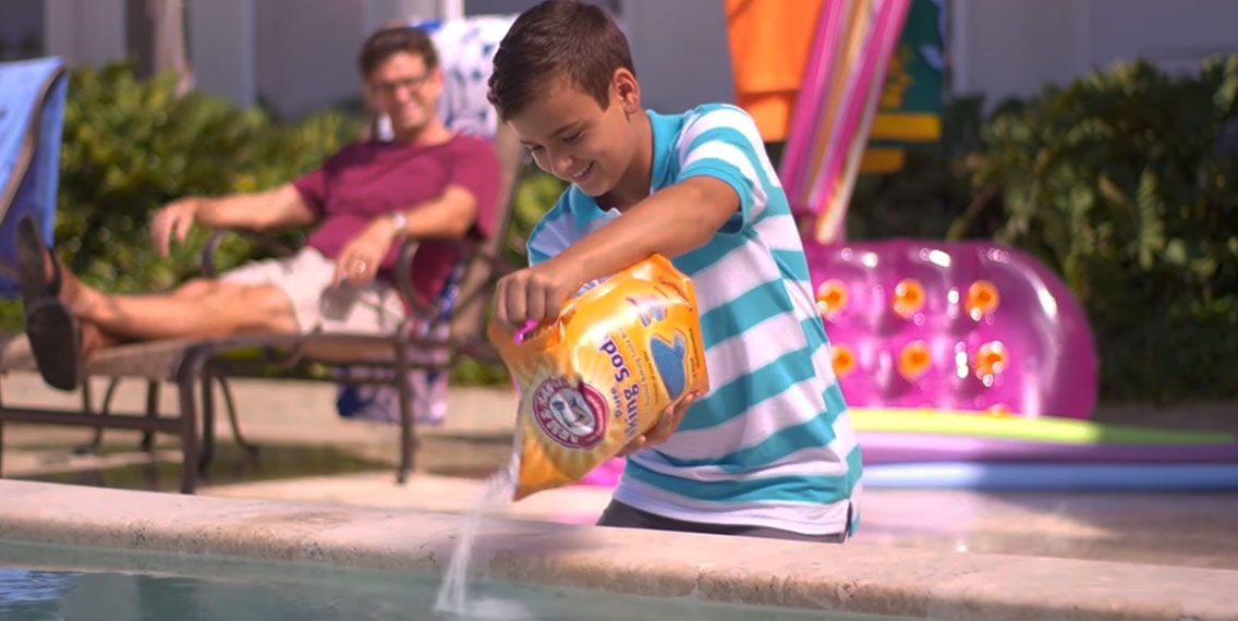 A boy adding baking soda to the swimming pool water