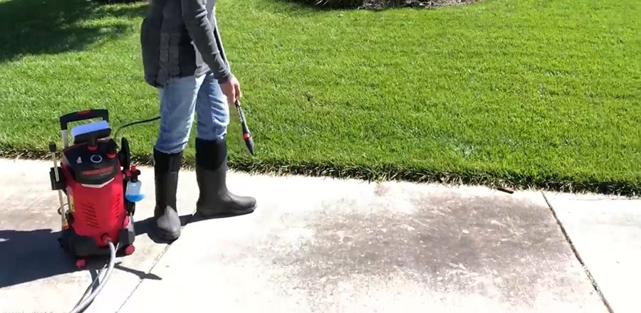 Man washes a sidewalk with the pressure washer