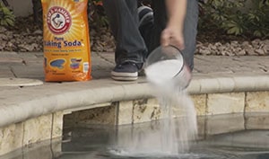 Man adds the baking soda to the pool