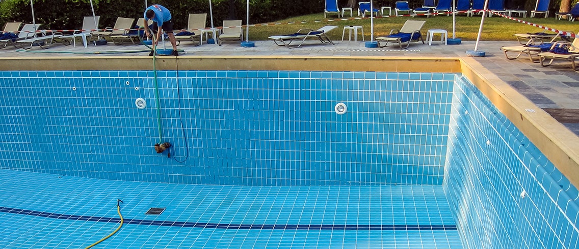 Man drains the pool for maintenance.