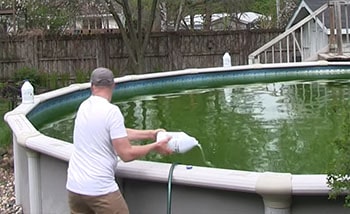 Man adds chemicals to his above-ground pool