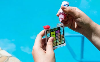 Pool owner adds chemical reagent to water test kit.