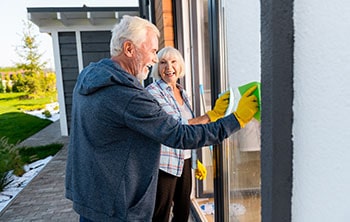 Couple cleaning exterior window of their house.