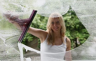 A young woman cleans the window.