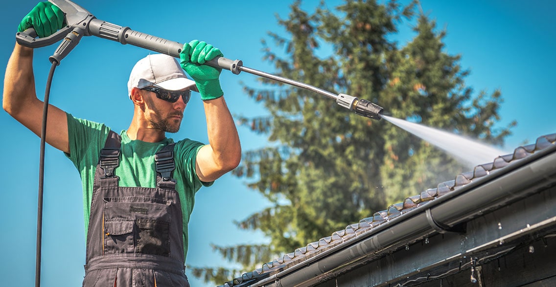 Man washing the roof of the house.