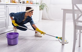 A pretty woman mops the kitchen floor