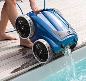 Woman removes pool cleaning robot from the swimming pool