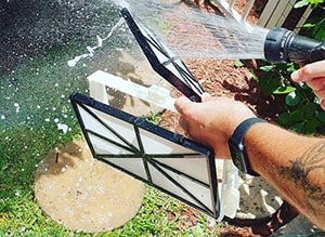 Man hosing the filter of the pool cleaning robot.