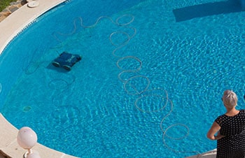 Woman looks how robotic pool cleaner do its job