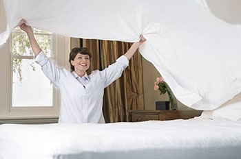 Smiling woman making bed.