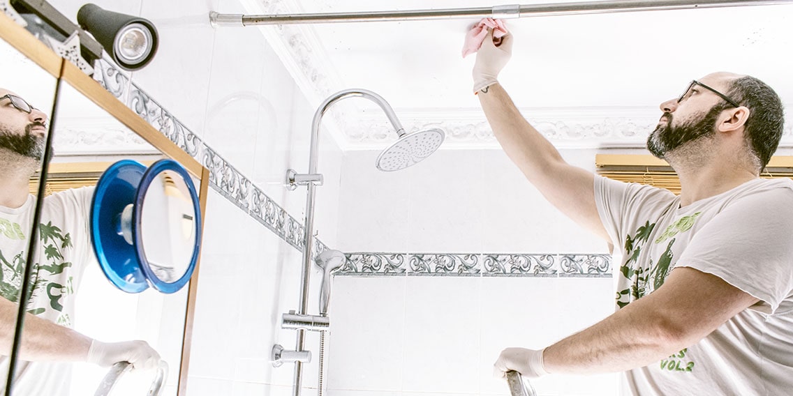 Man cleaning mold stains in the bathroom.