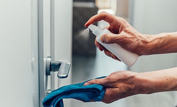 Woman disinfects the door handle.