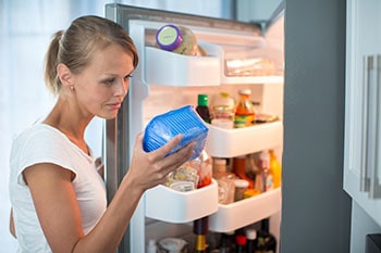 Woman examining food from her fridge.