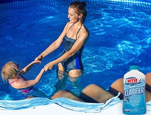 Pool clarifier bottle and a mother playing with her child in the clean swimming pool