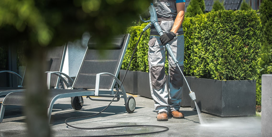 A man cleans the house patio using a pressure washer.