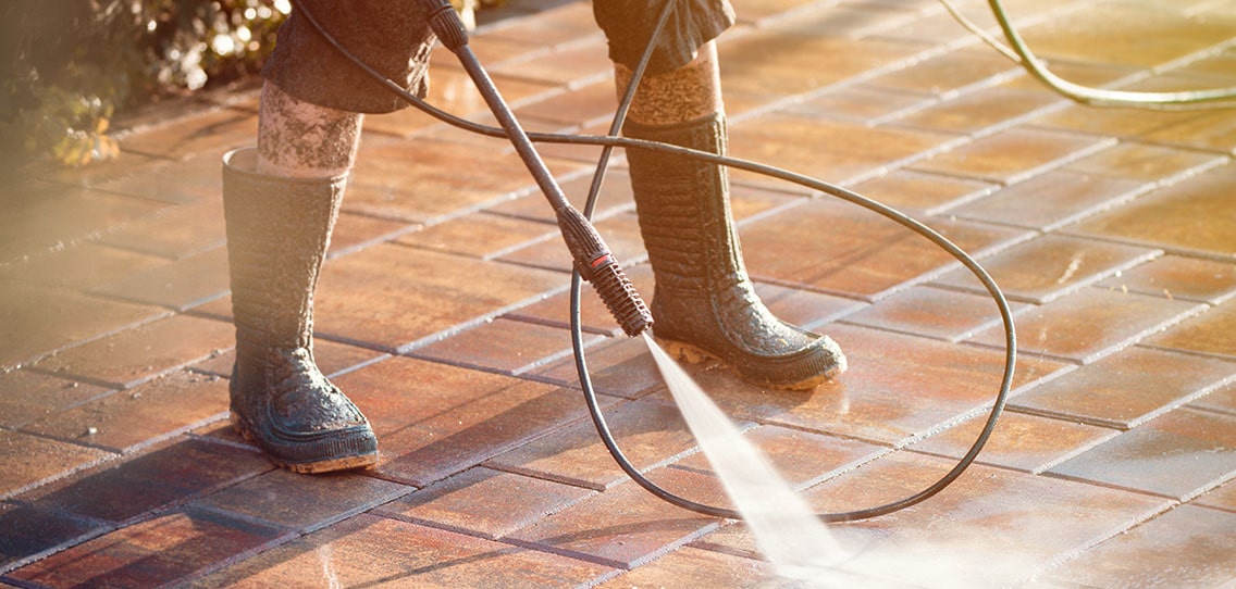 Man cleaning patio with high-pressure water.