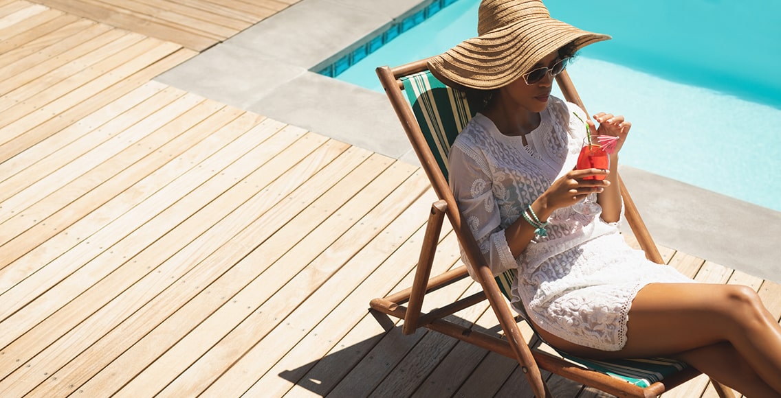 Woman is spending time poolside enjoying drink