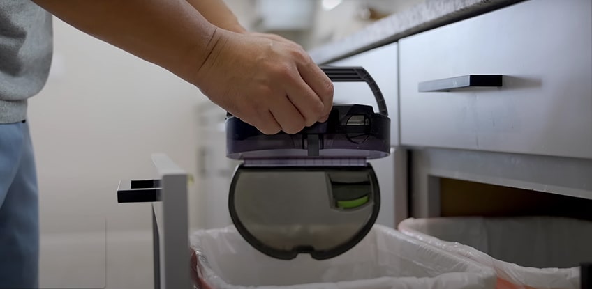 A man empties all dirt from the robot vacuum cleaner