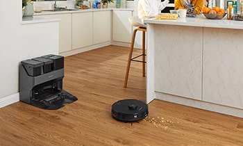 Roborock is cleaning the floor in the kitchen where hardwood floor.
