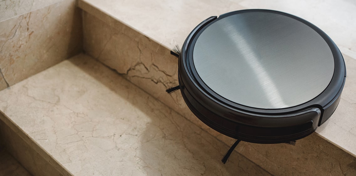 Robot vacuum cleaner is cleaning the floor near the stairs